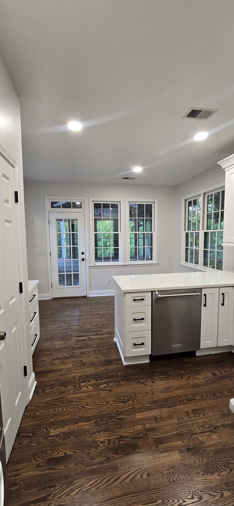 Modern kitchen with refinished dark hardwood floors meeting clean white trim
